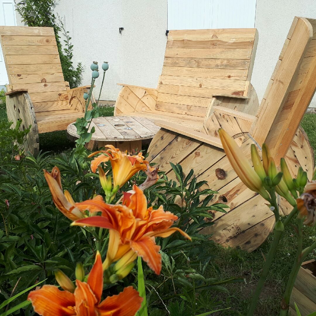 Fauteuils Adirondack et table touret en bois de palette, au milieu des lys orange en plein été